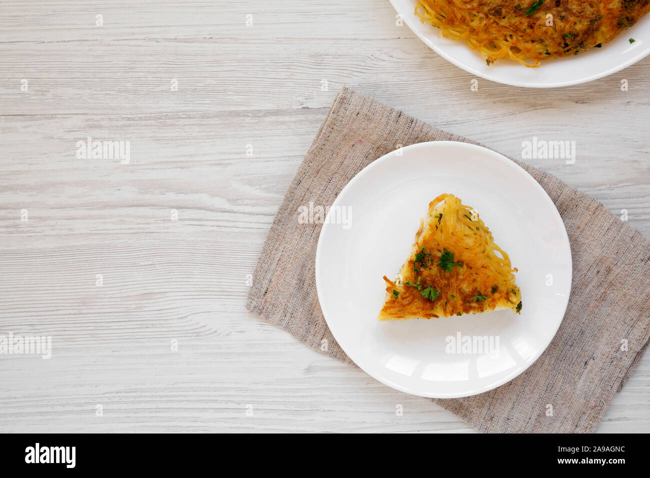 Homemade spaghetti omelette on a white plate on a white wooden table, top view. Flat lay, overhead, from above. Copy space. Stock Photo