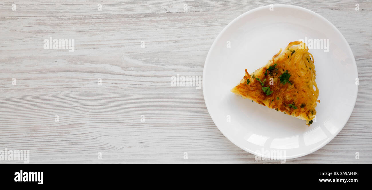 Homemade spaghetti omelette on a white plate on a white wooden surface, top view. Flat lay, overhead, from above. Space for text. Stock Photo