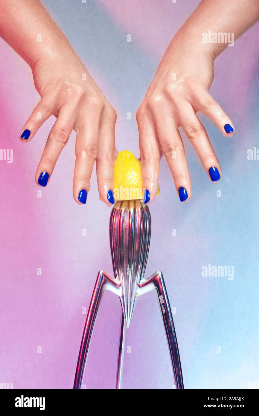 Mains manucurées de bleu tenant/ jouant avec un citron jaune / Manicured hands of blue holding / playing with a yellow lemon Stock Photo