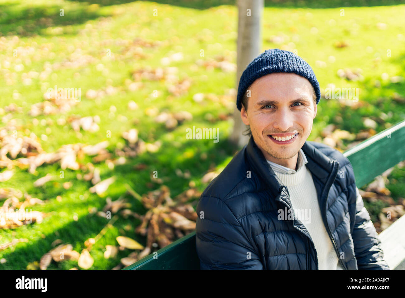 Happy young man on a bench during a sunny autumn day. Stock Photo