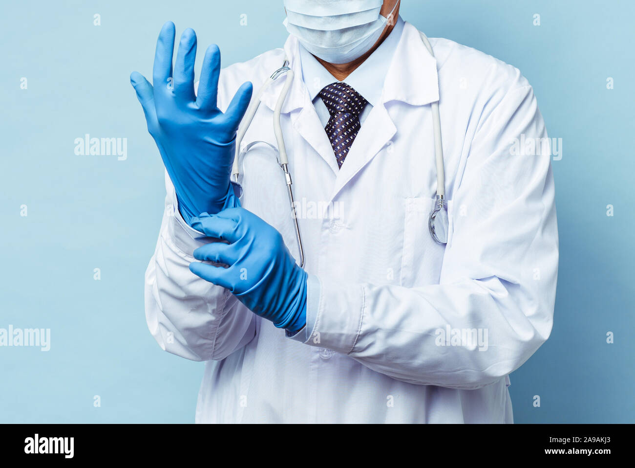 doctor puts on rubber gloves, healthcare and medicine. Isolate on blue background Stock Photo