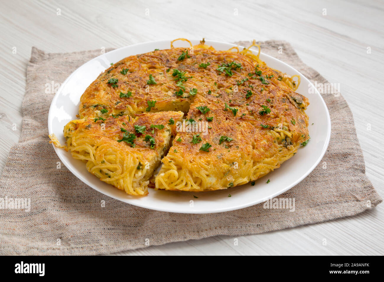 Homemade spaghetti omelette on a white plate, side view. Close-up. Stock Photo