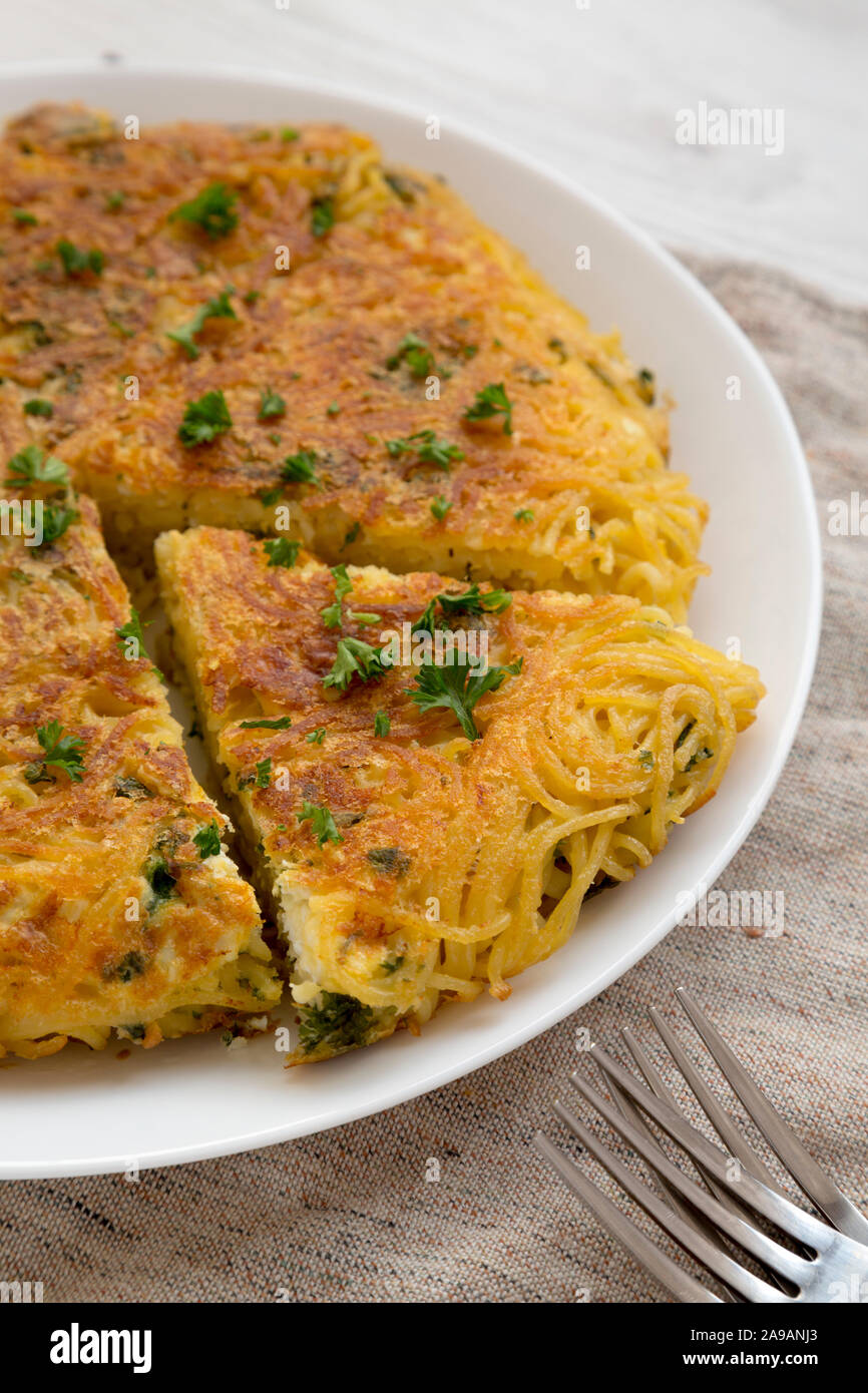 Homemade spaghetti omelette on a white plate, low angle view. Close-up. Stock Photo