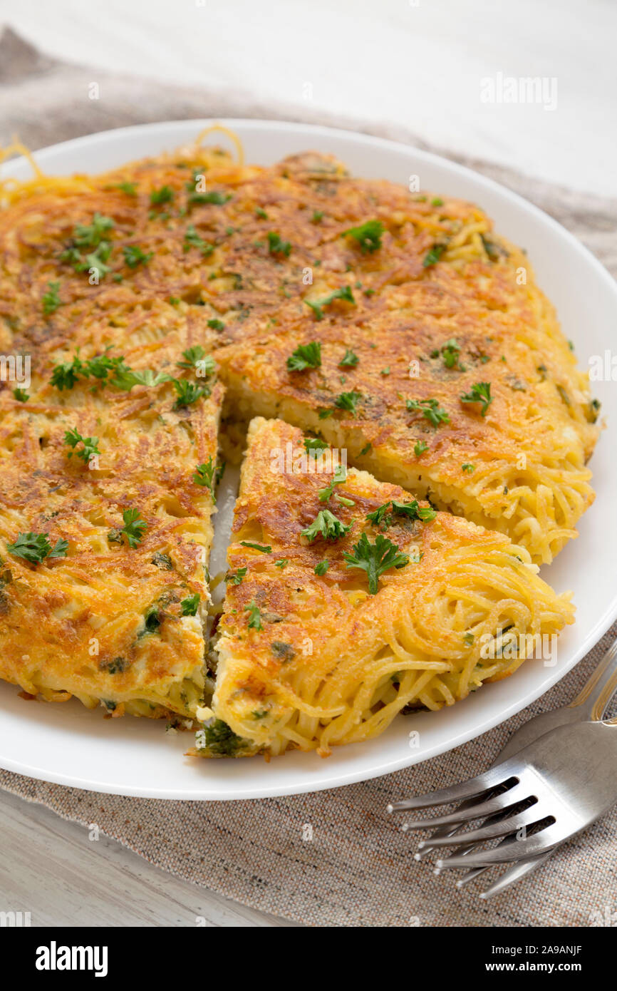 Homemade spaghetti omelette on a white plate, low angle view. Closeup. Stock Photo