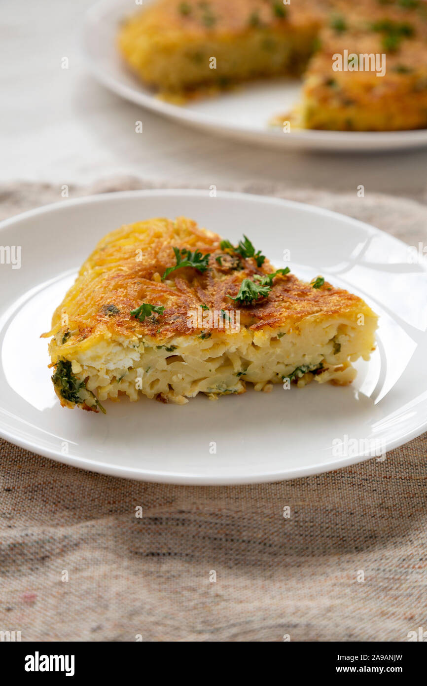 Homemade spaghetti omelette on a white plate, side view. Close-up. Stock Photo