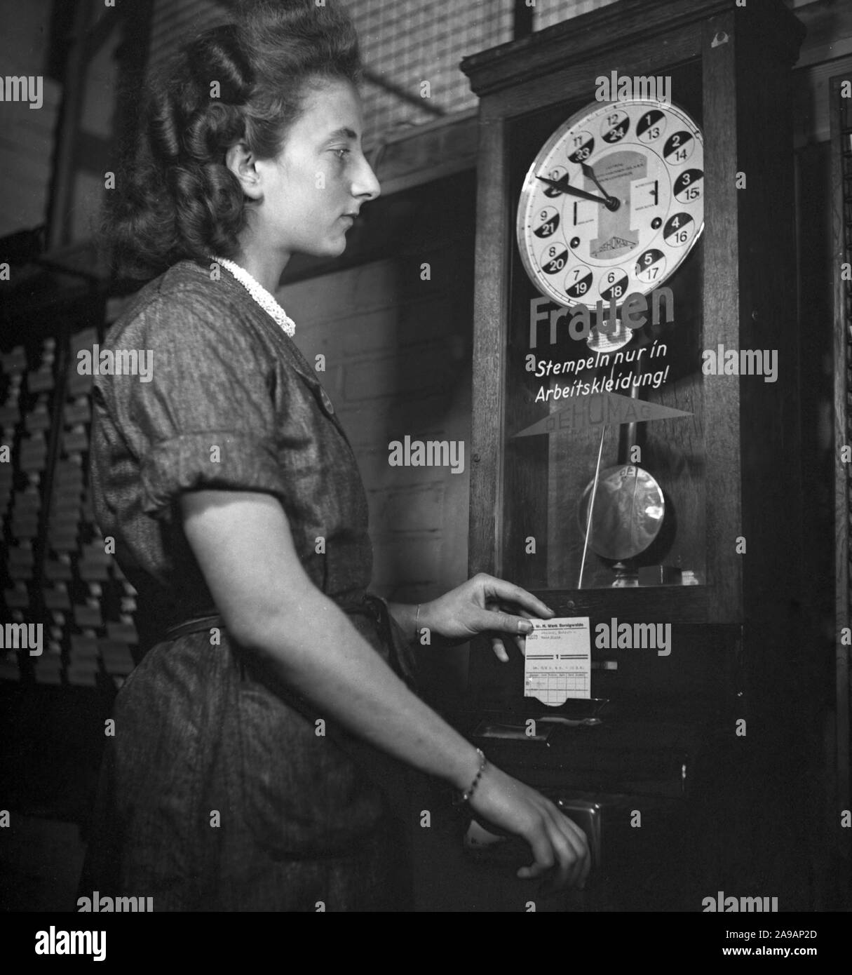 A woman at the attendance clock, Germany 1940s Stock Photo