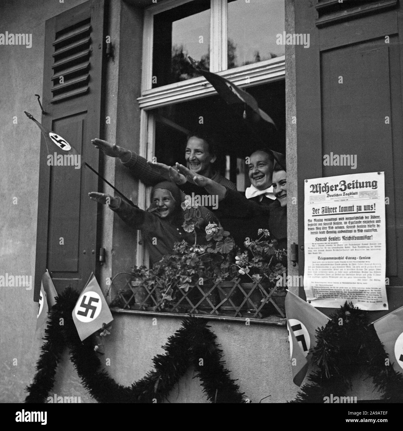 People cheering to Fuehrer and chancellor Adolf Hitler out of their windows visiting the city of Asch in Sudetenland county, Germany 1930s. Stock Photo