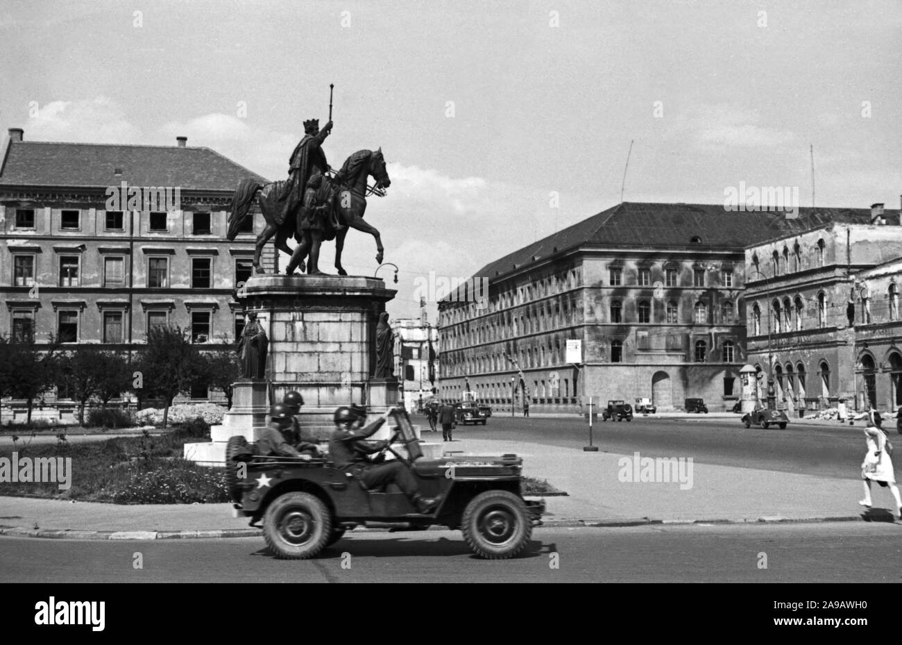 A jeep with American GI soldiers cruising through Munich at Odeonsplatz square, Germany 1940s. Stock Photo