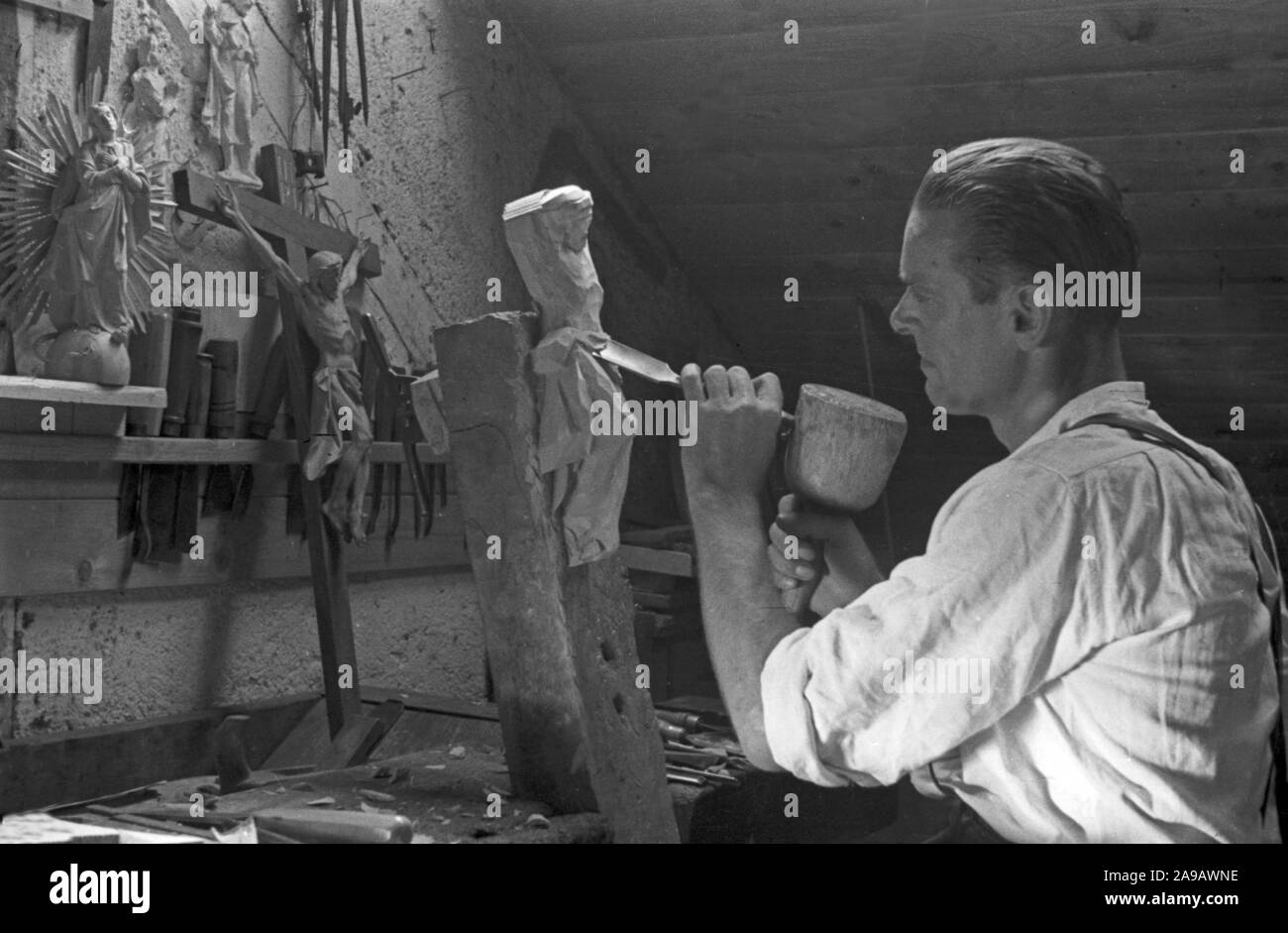 A wood carver creating a statuette, Germany 1940s. Stock Photo