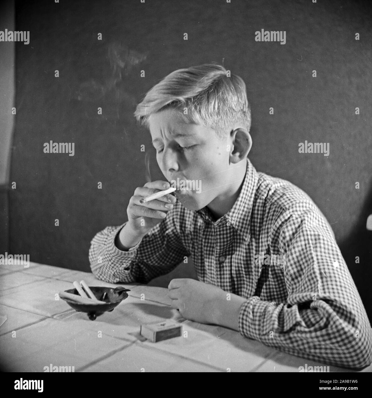 A curious boy trying his first cigarette, Germany 1940s Stock Photo