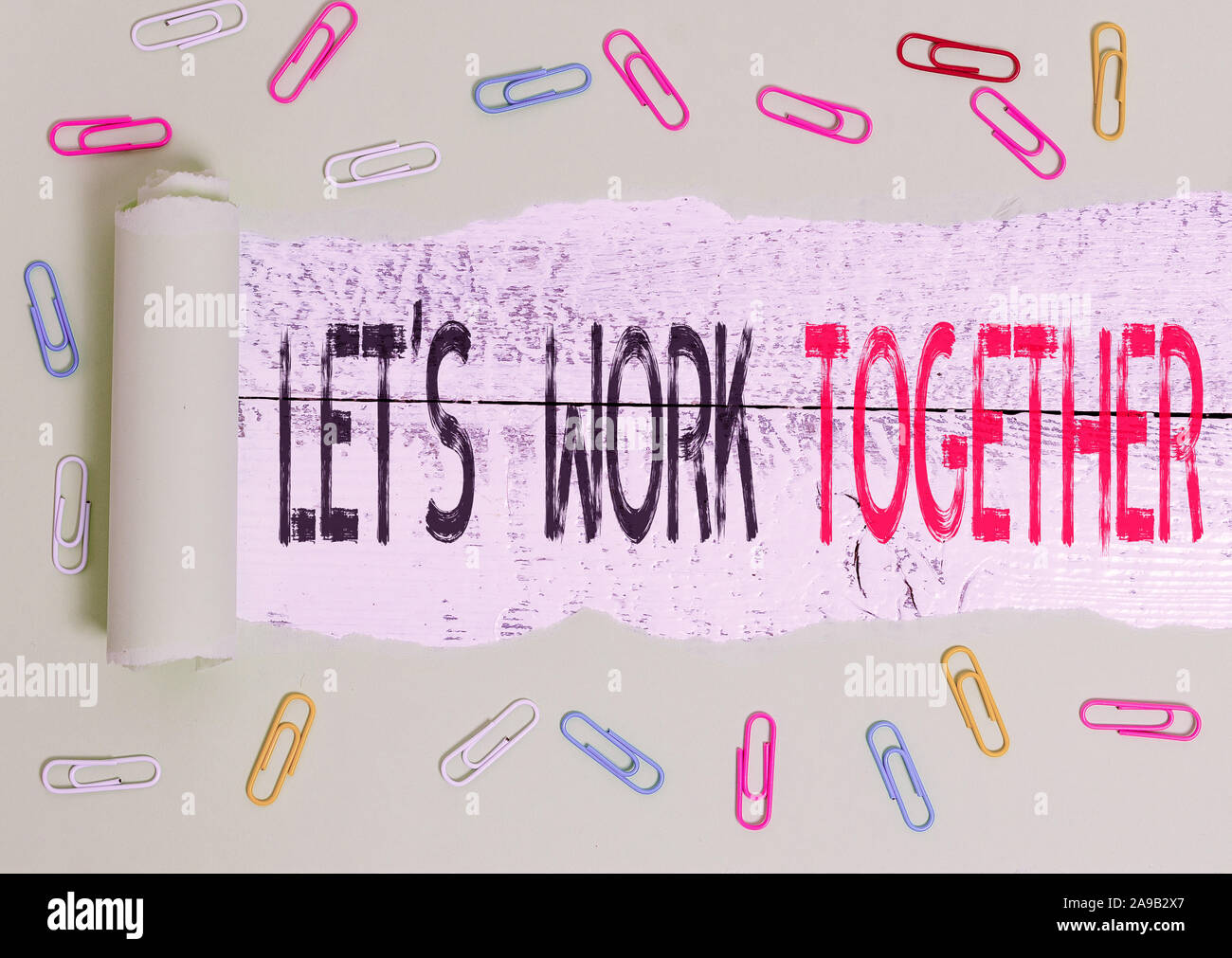Word writing text Let S Work Together. Business photo showcasing Unite and Join Forces to Achieve a Common Goal Paper clip and torn cardboard placed a Stock Photo
