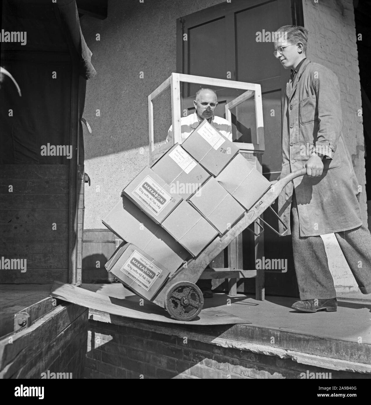 Apprentice loading a lorry with maccaroni noodles, Germany 1940s. Stock Photo