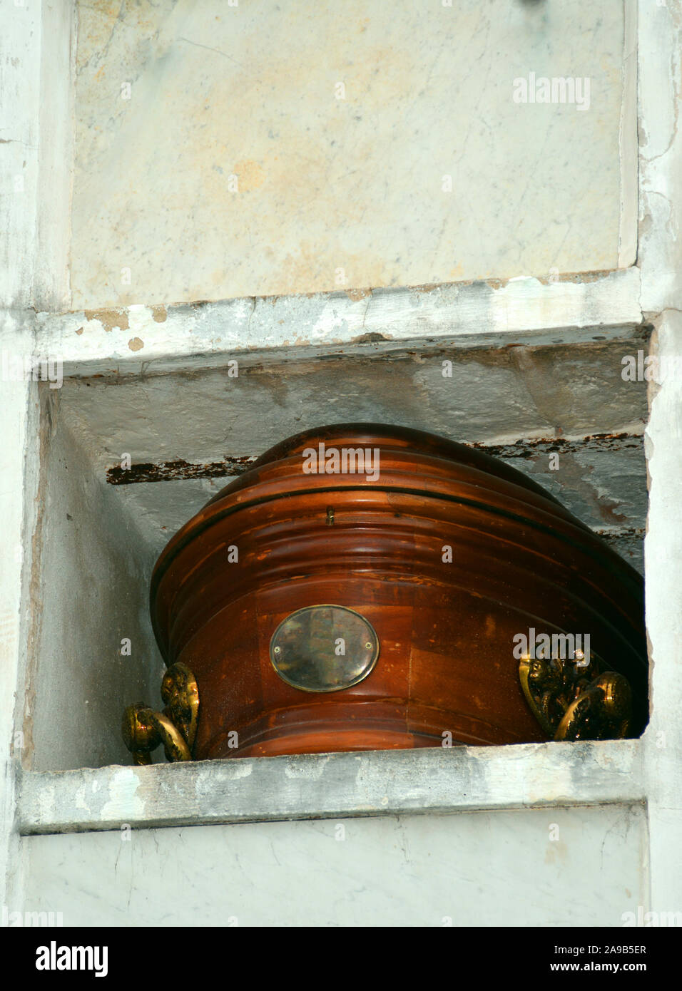 An old casket is visible in the storage space of the mausoleum at the