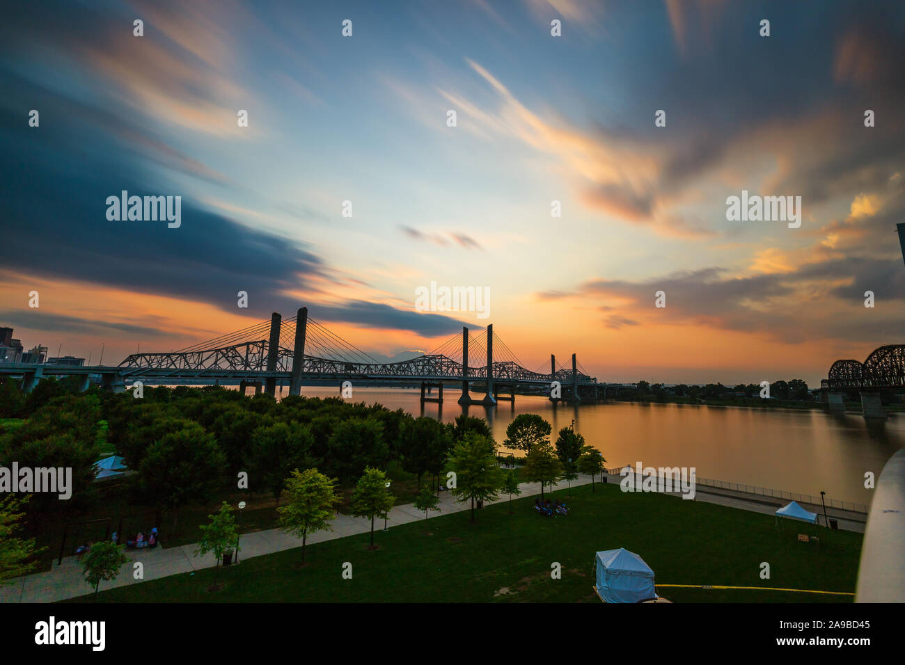 The Abraham Lincoln Bridge crosses the Ohio River that connects Kentucky and Indiana for motor vehicles. Long exposure sky and water movement. Stock Photo