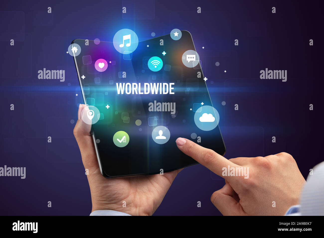 Businessman holding a foldable smartphone with WORLDWIDE inscription, social media concept Stock Photo