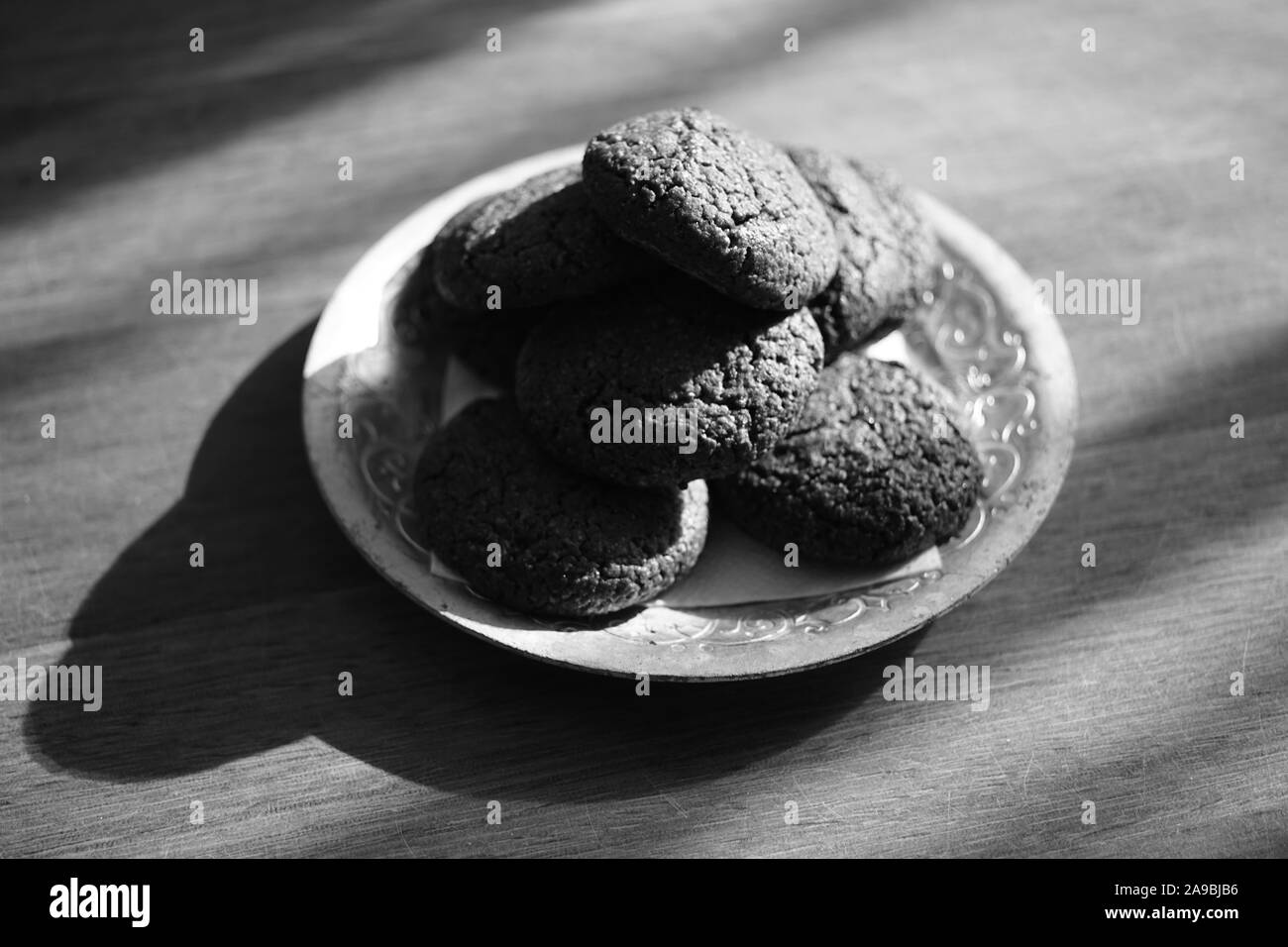 Oatmeal cookies in a silver plate on a wooden table, bw photo. Stock Photo