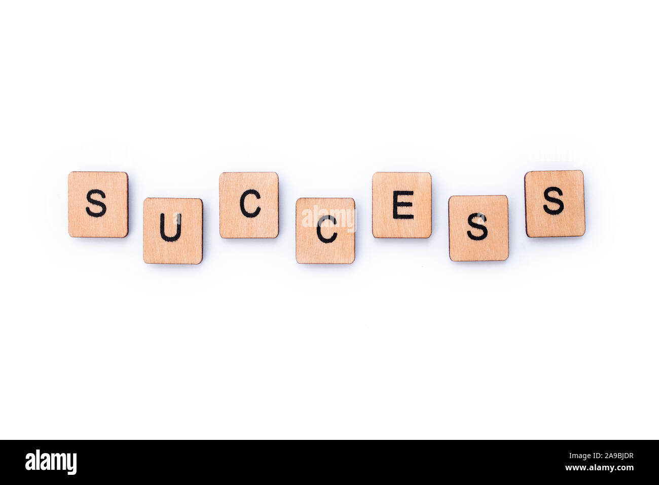 The word SUCCESS, spelt with wooden letter tiles over a white background. Stock Photo