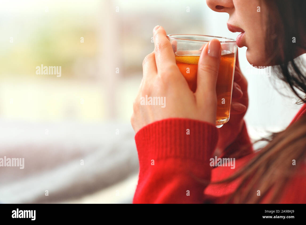 Young woman relaxing holding cup with lemon tea. Girl dreams looking ...