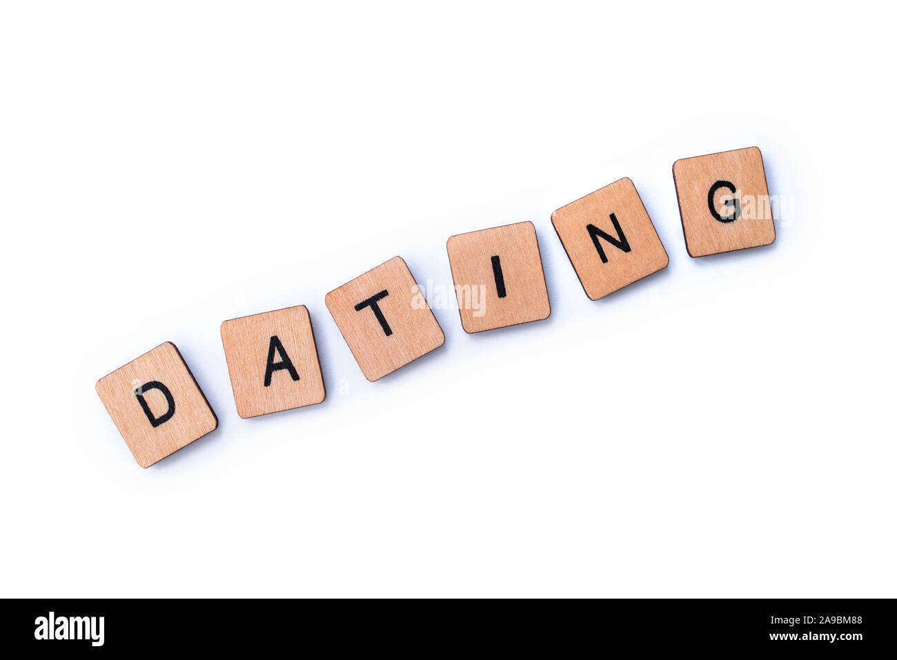 The word DATING, spelt with wooden letter tiles over a white background ...