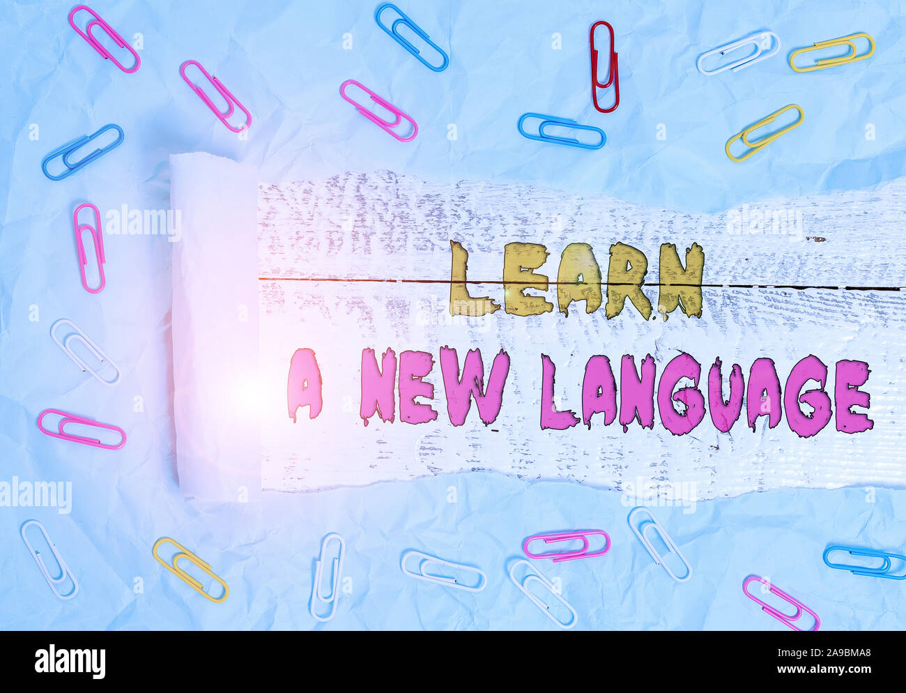 Writing note showing Learn A New Language. Business concept for Study Words other than the Native Mother Tongue Paper clip and torn cardboard on wood Stock Photo