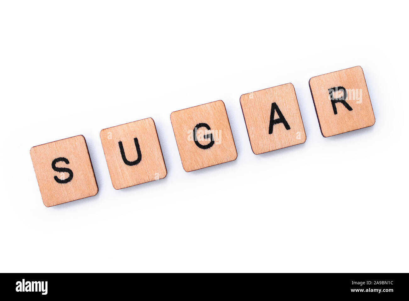 The word SUGAR, spelt with wooden letter tiles over a white background. Stock Photo