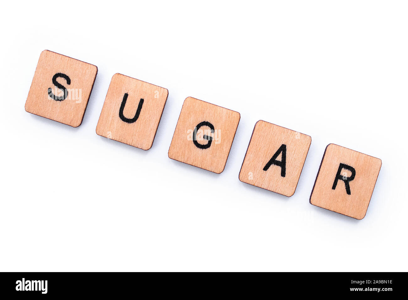 The word SUGAR, spelt with wooden letter tiles over a white background. Stock Photo