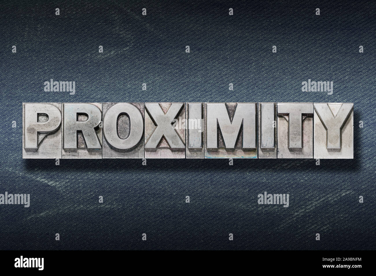 proximity word made from metallic letterpress on dark jeans background Stock Photo