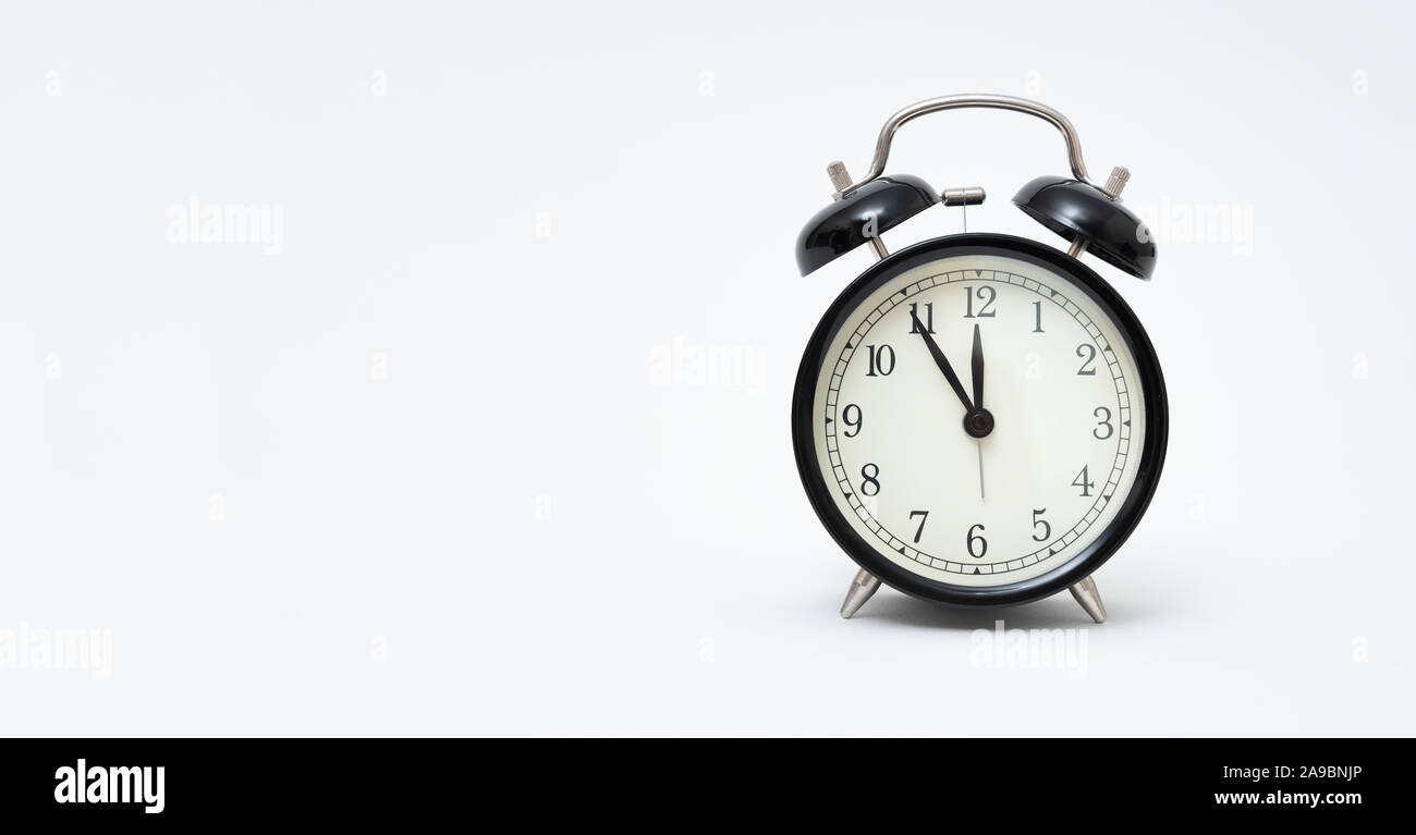 Retro alarm clock with five minutes to twelve o'clock. Clock isolated