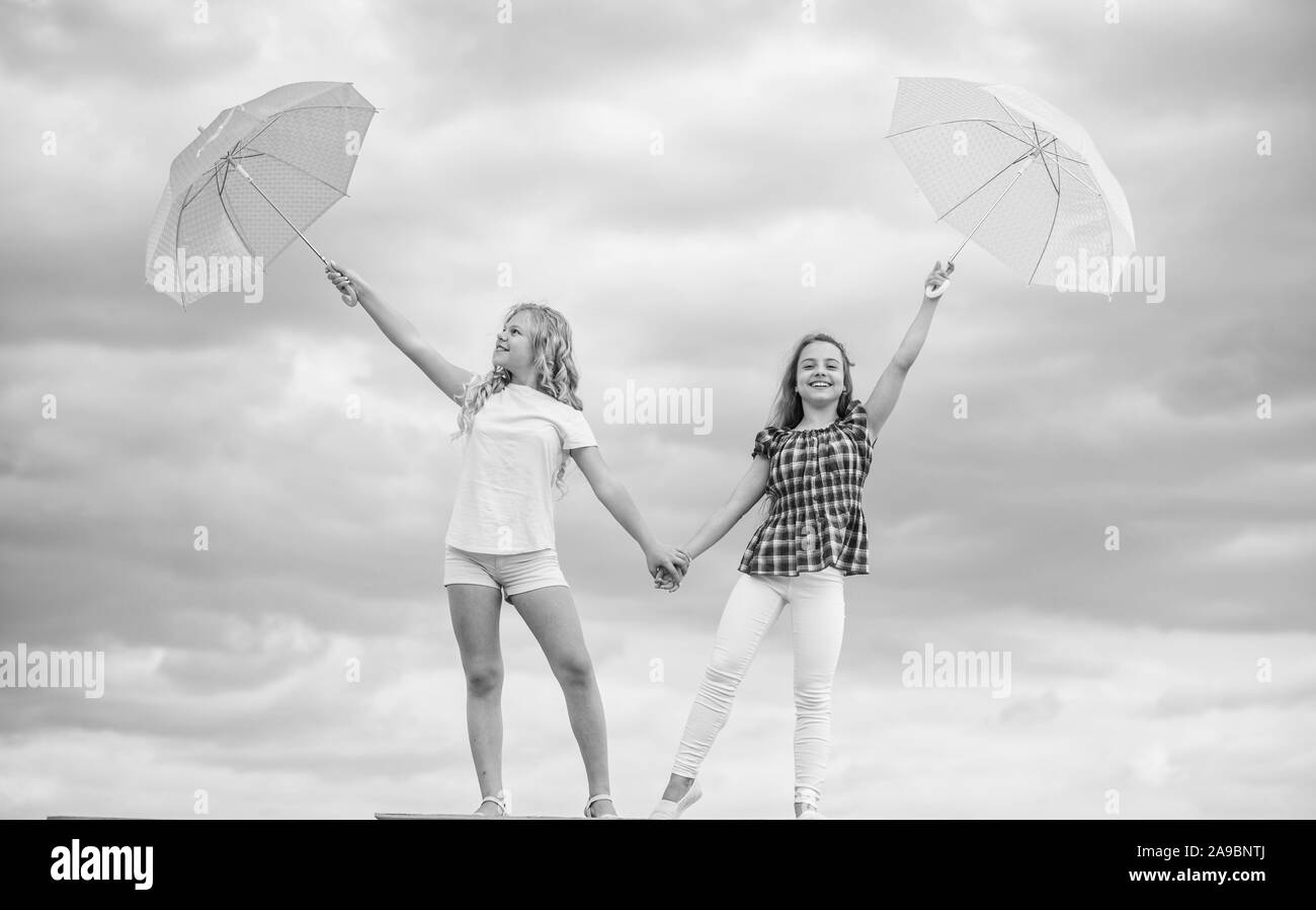 Going crazy together. positive and bright mood. best friends. school time. autumn season. rainy weather forecast. fall fashion. Feeling protected at this autumn day. happy small girls with umbrella. Stock Photo