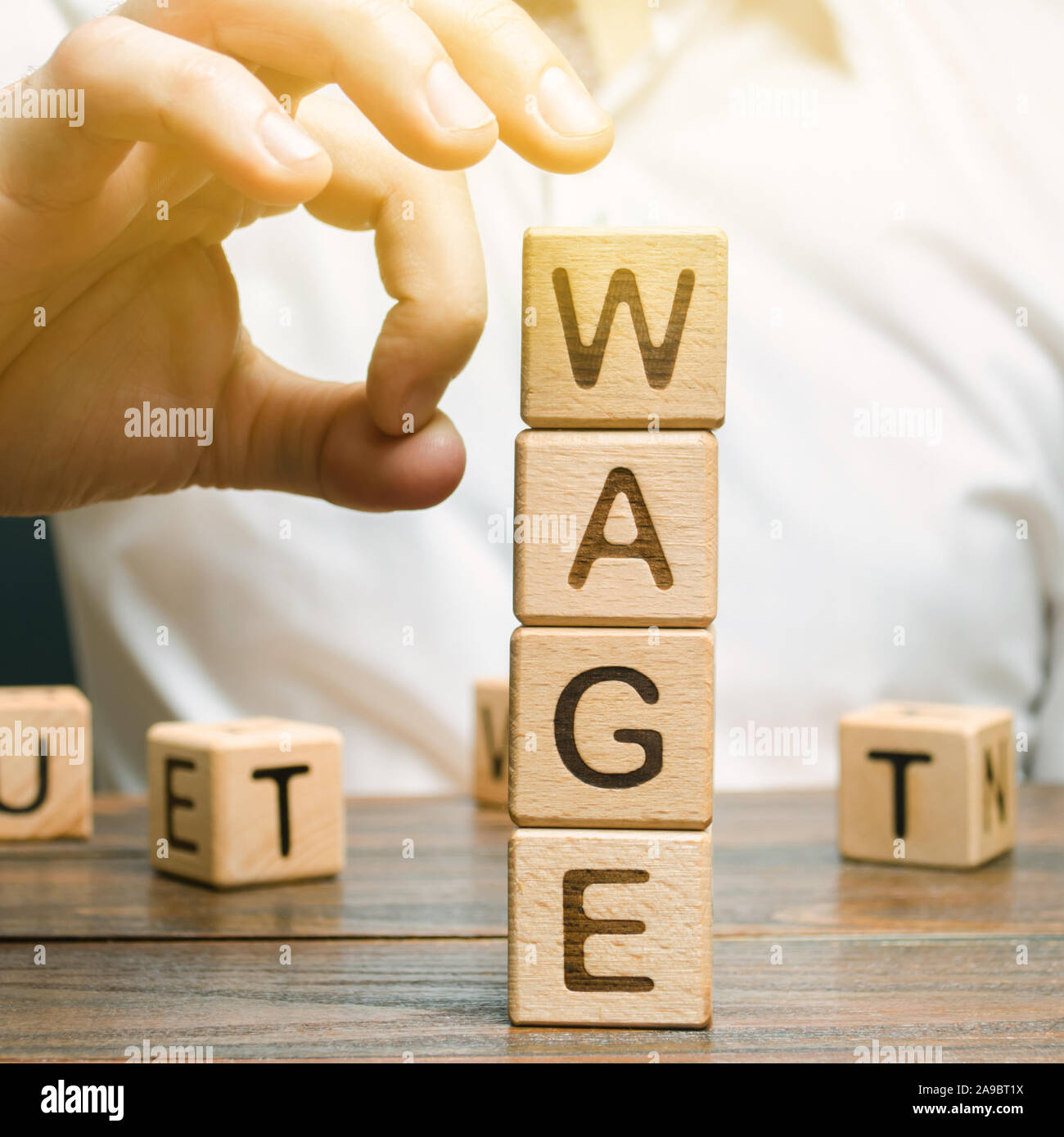 Hand of a businessman removes wooden blocks with the word Wage 