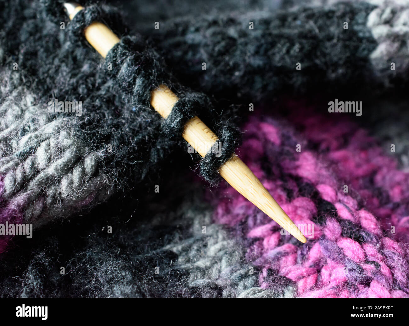 Closeup of Knitting Needle and Stitch Loops in Black Pink and Grey Variegated Wool Stock Photo
