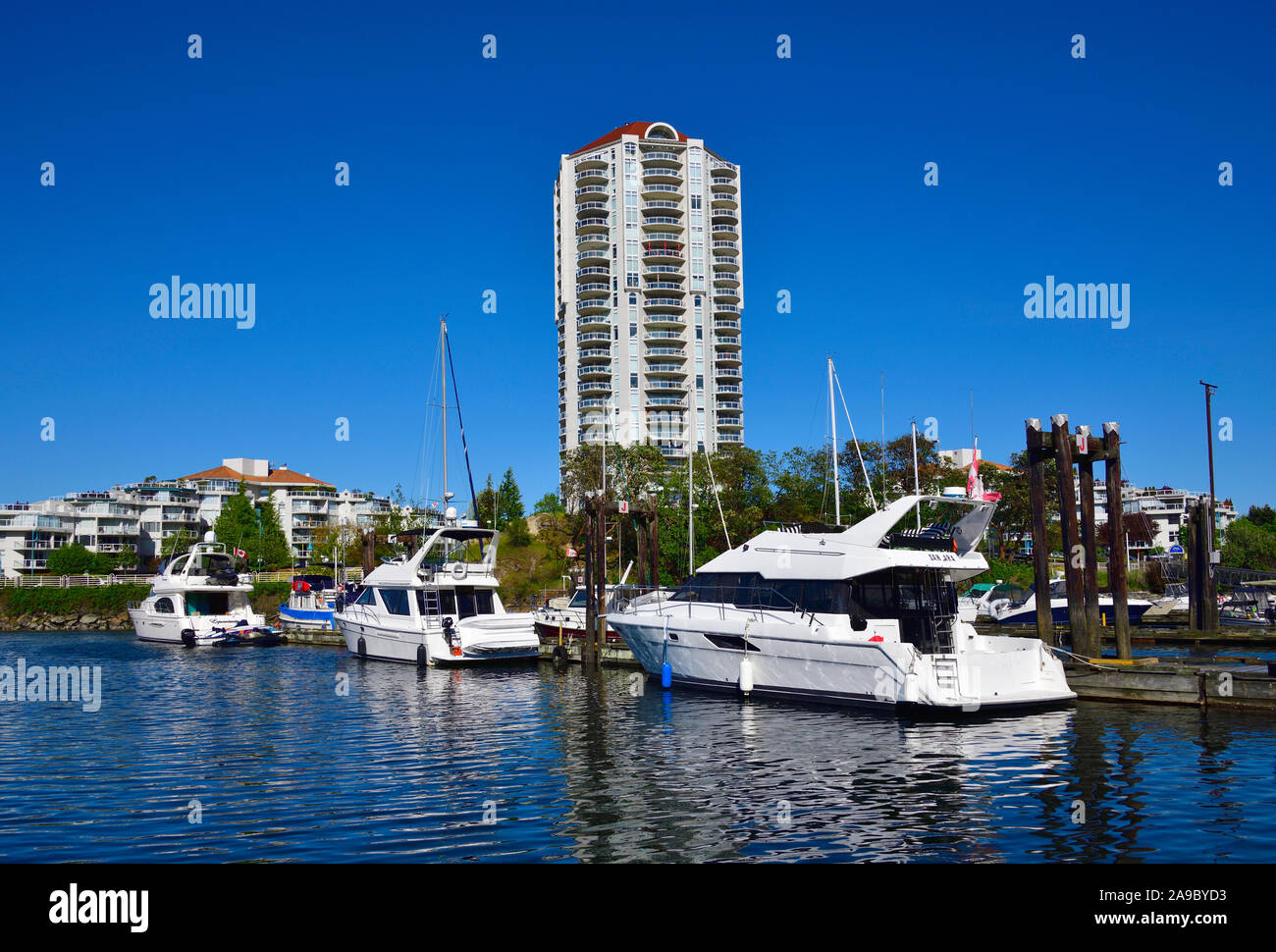 Motor boats tied up at a dock in Nanaimo harbour with the condominium tower known as the Beacon in the background on Vancouver Island Stock Photo