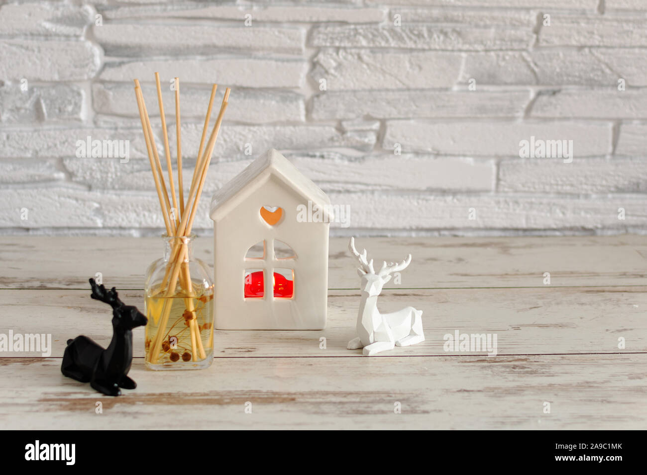 Candles and Christmas decoration on white wooden table with bokeh lights over brick wall. Sweet hime, Christmas time. Stock Photo