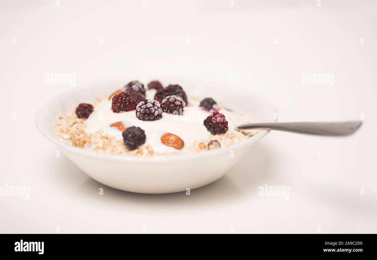 Oat cereal breakfast bowl with plain yogurt, frozen berries and almonds