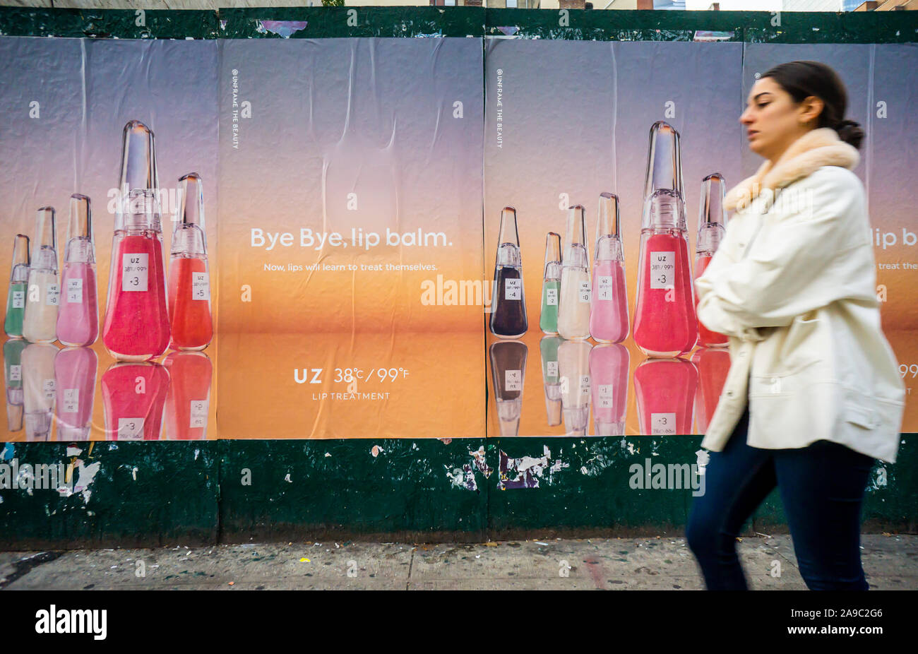 People walk past advertising posters for UZ brand lip balm in New York on Monday, November 11, 2019. (© Richard B. Levine) Stock Photo