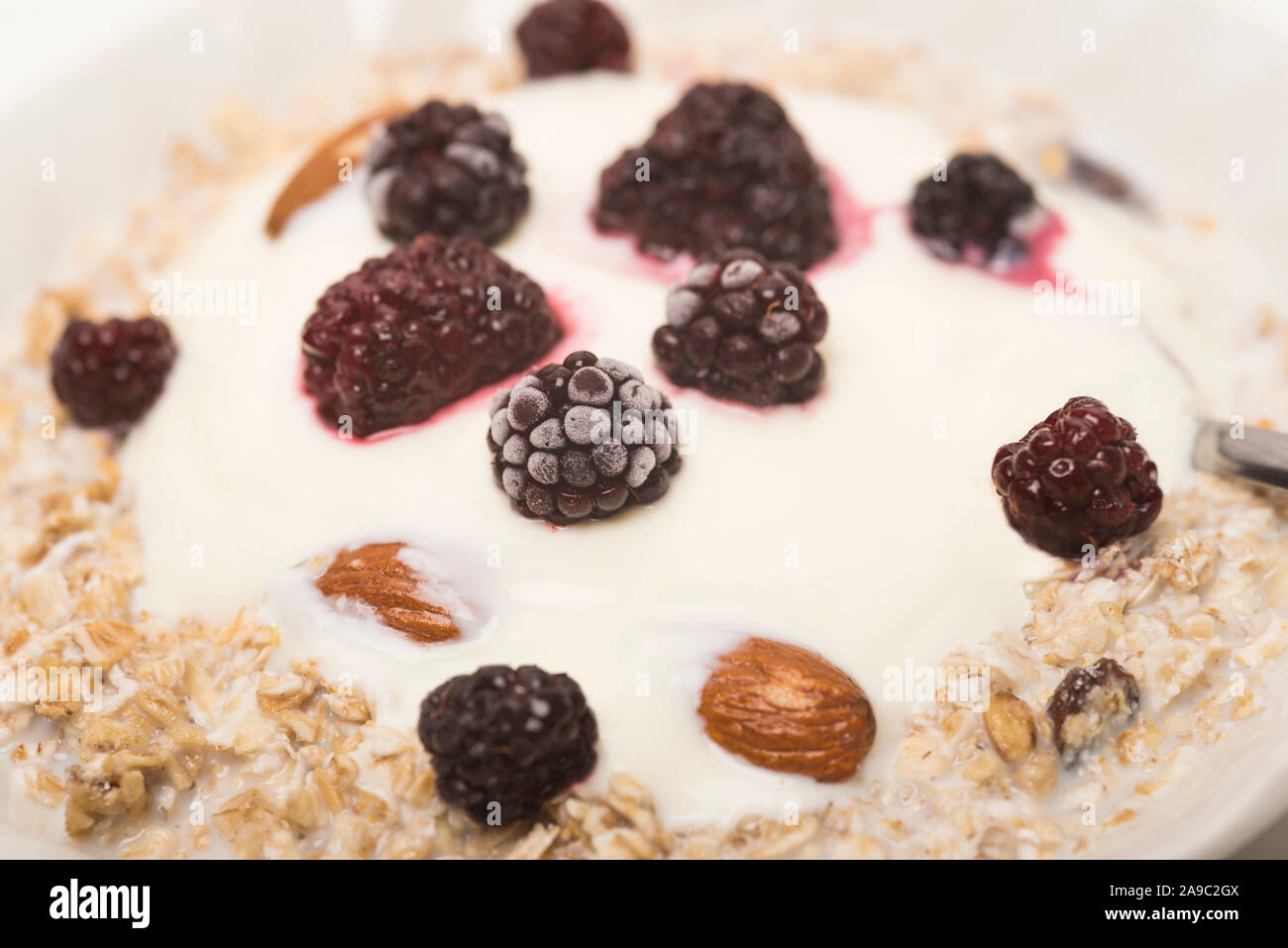 Oat cereal breakfast bowl with plain yogurt, frozen berries and almonds