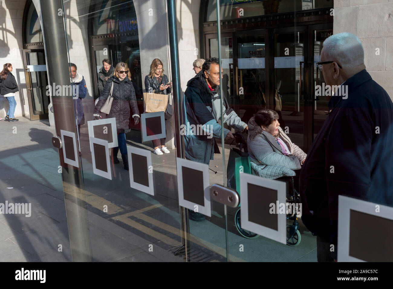 Londoners wait for the next bus service at a bus stop in Kingston town centre, on 13th November 2019, in London, England. Stock Photo