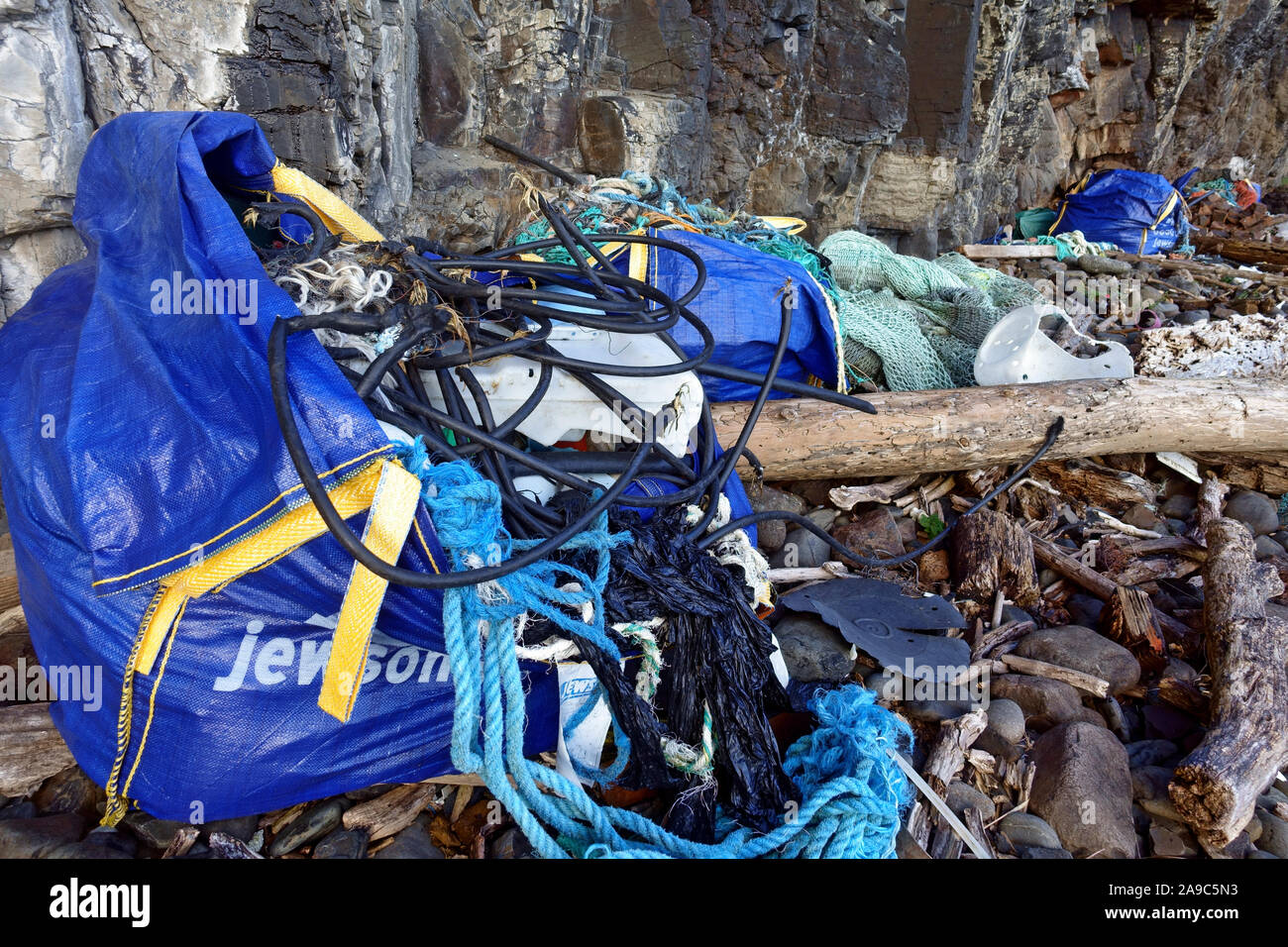 Beach tidy exercise cleaning up debris of ropes, plastic, wood washed up on a remote beach on the Isle of Mull in the Inner Hebrides of Scotland Stock Photo