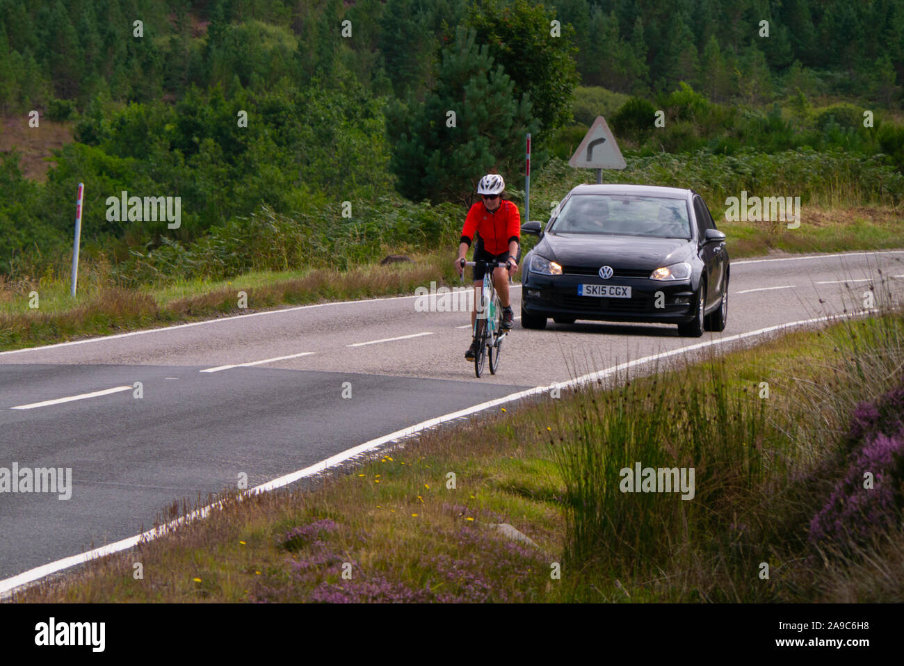 Female cyclist riding up a hill in Sutherland Scotland UK Stock Photo