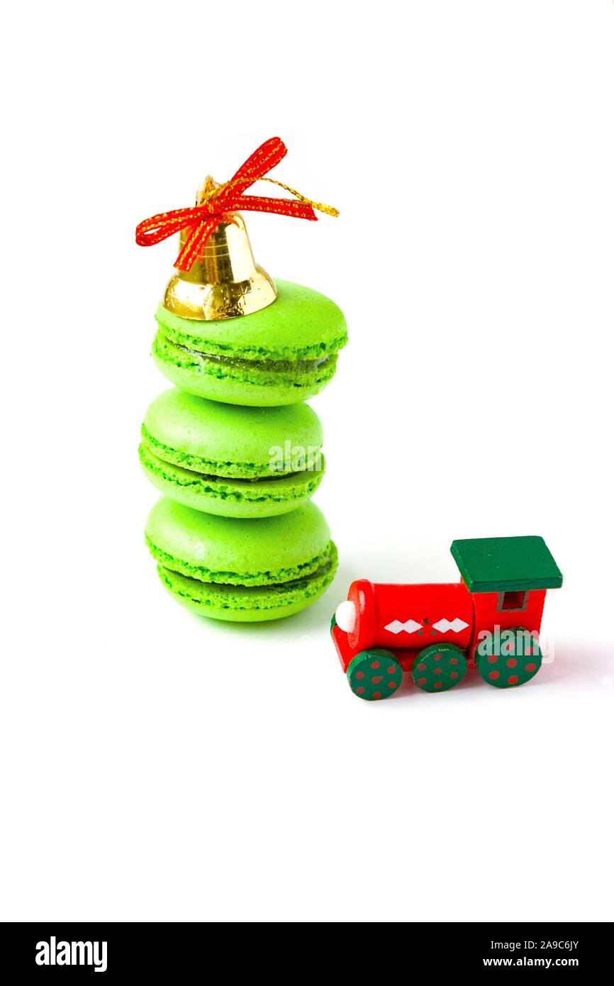 Green macarones with golden christmas bell and new year toy train on white background Stock Photo