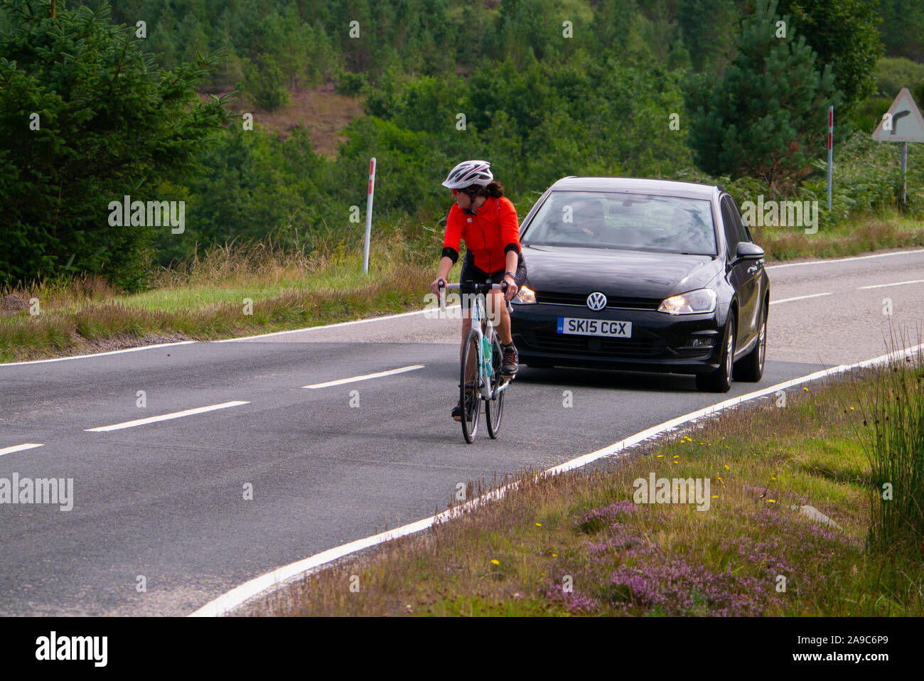 Female cyclist riding up a hill in Sutherland Scotland UK Stock Photo