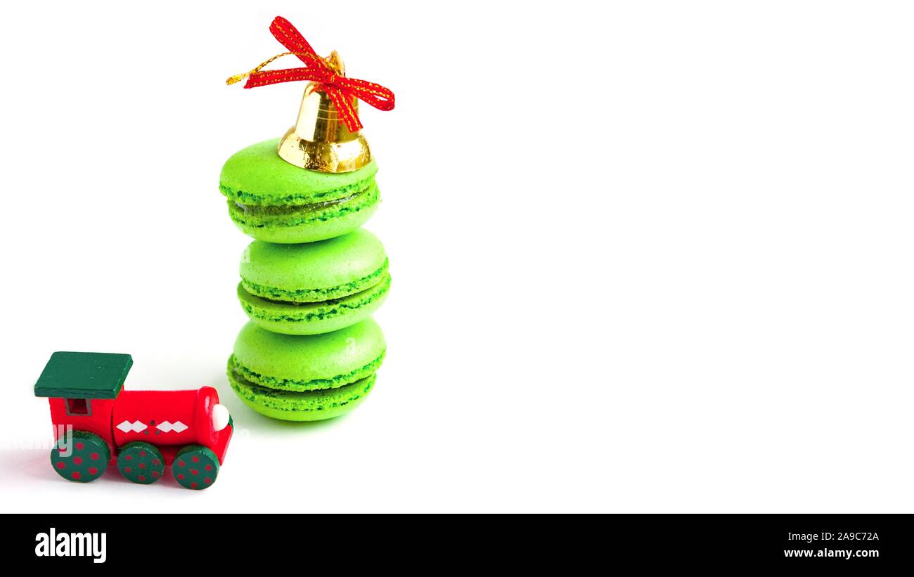 Green macarones with golden christmas bell and new year toy train on white background Stock Photo