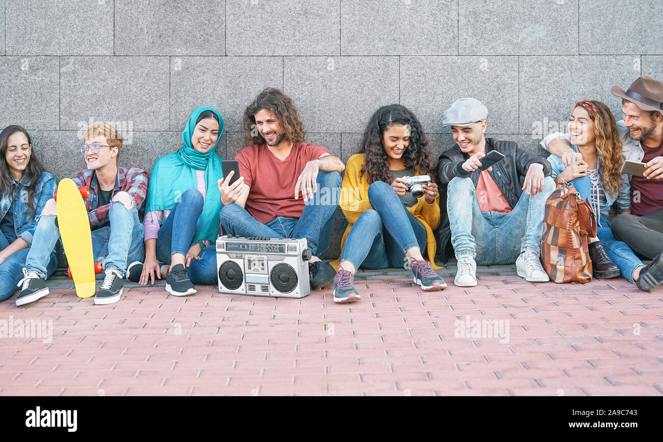 Group of diverse friends having fun outdoor - Millennial young people using mobile phones taking photo and listening music with vintage stereo Stock Photo