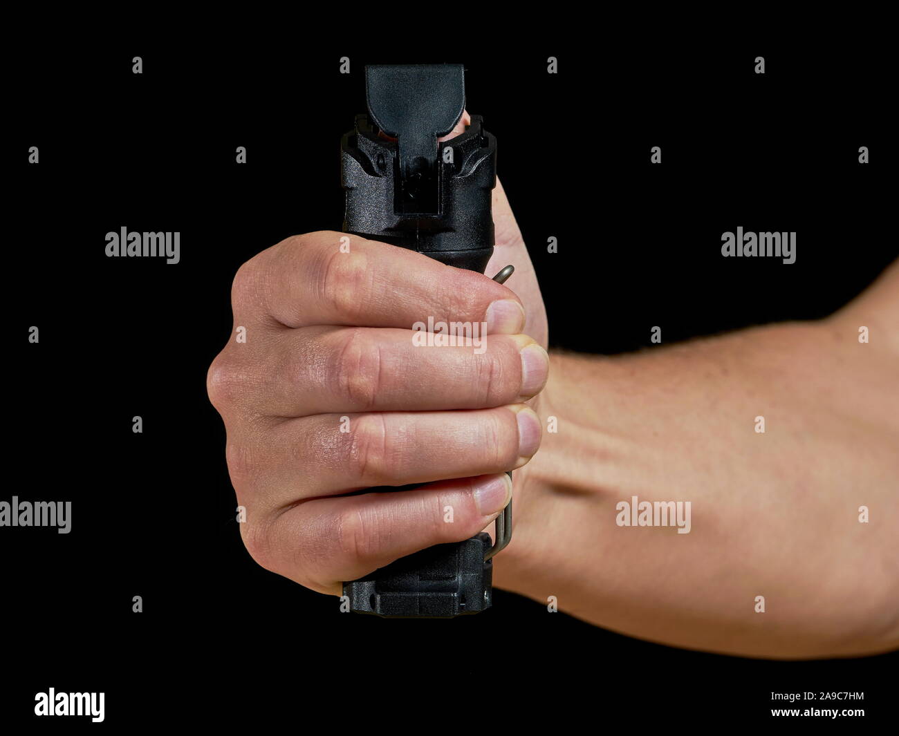 male aiming pepper spray towards camera on black background Stock Photo