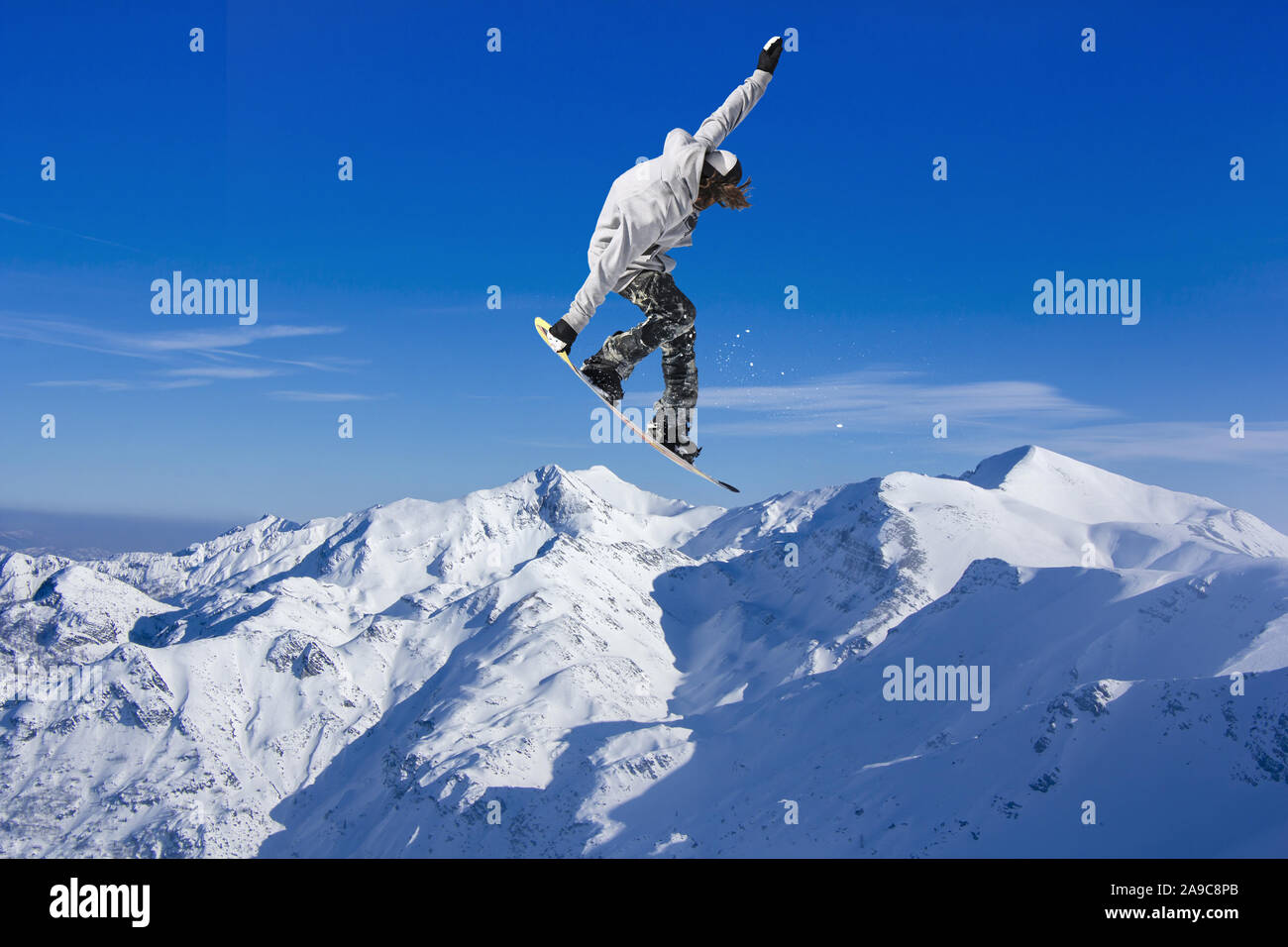 Skier Snowboarder jumping through air with blue sky in background Stock Photo