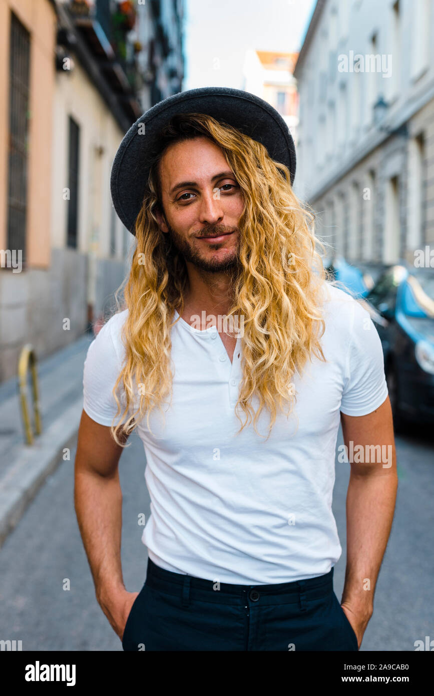 Stylish Trendy Long Blonde Haired Guy Smiling In The Street With A