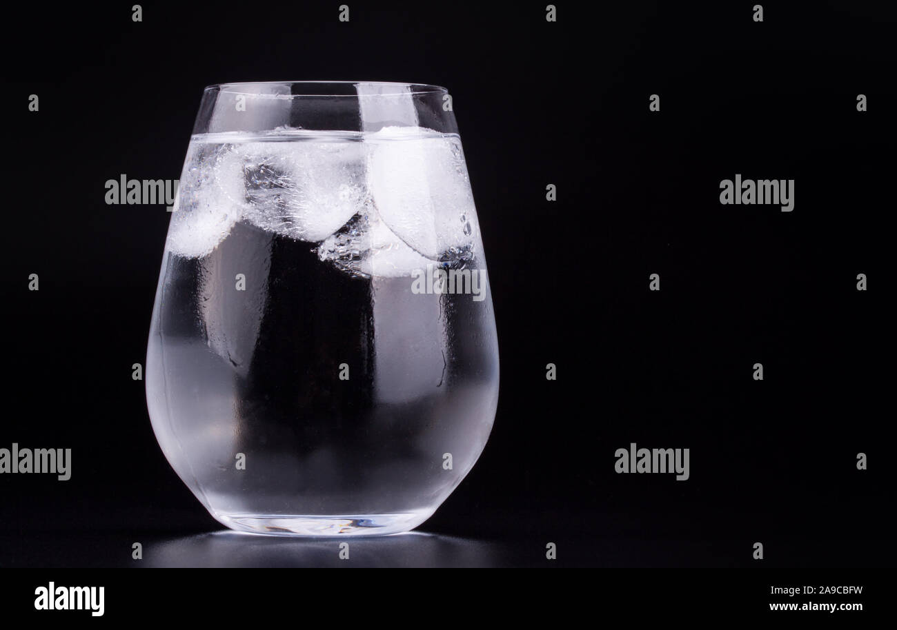 Big glass of water with ice cubes, black background Stock Photo - Alamy
