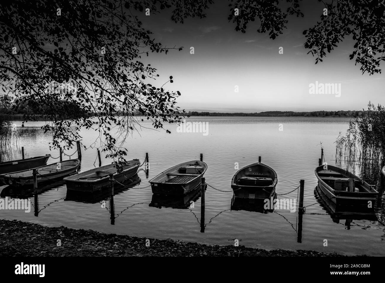 some rowboats lie at a lake in the north of Germany in the morning in autumn Stock Photo