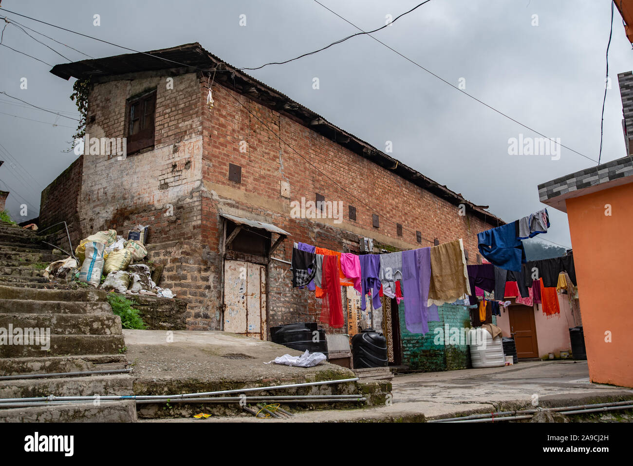 View of houses hugging the hillside in Shimla constructed close to each other. In the foreground clothes are being dried Stock Photo