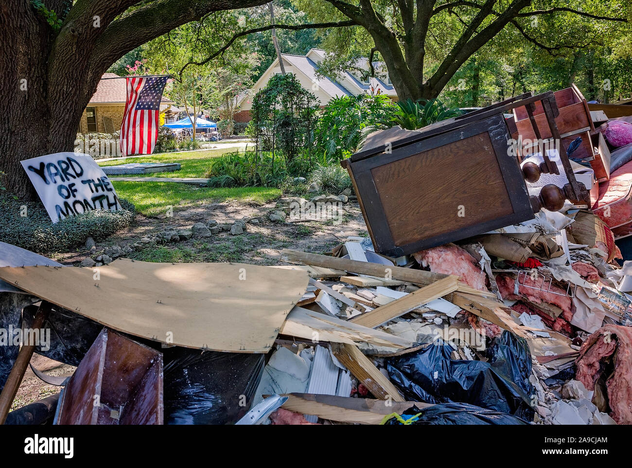 A “Yard of the Month” sign, nearly obscured by flood debris from Hurricane Harvey, leans against a tree, Sept. 6, 2017, in Houston, Texas. Stock Photo